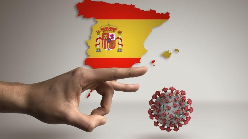 una mano caccia via un virus con la Spagna sullo sfondo Una mano caccia via un virus con la spagna sullo sfondo
