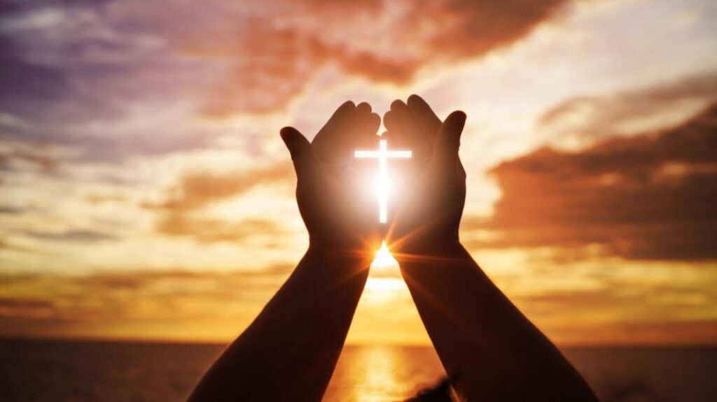 mani che formano una croce cattolica con la luce del sole mani che formano una croce cattolica con la luce del sole